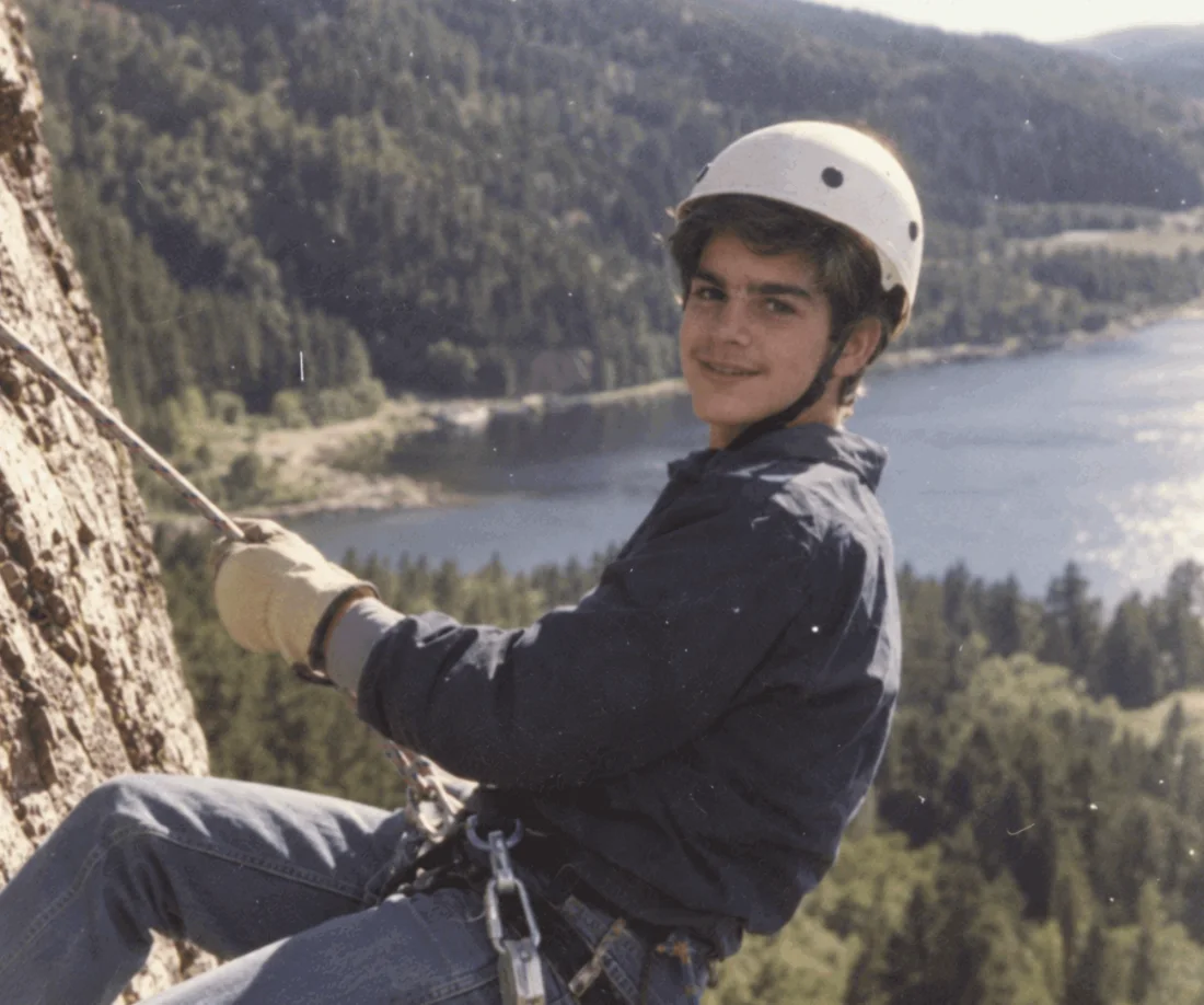 James at twelve, rappelling down a cliff above a lake